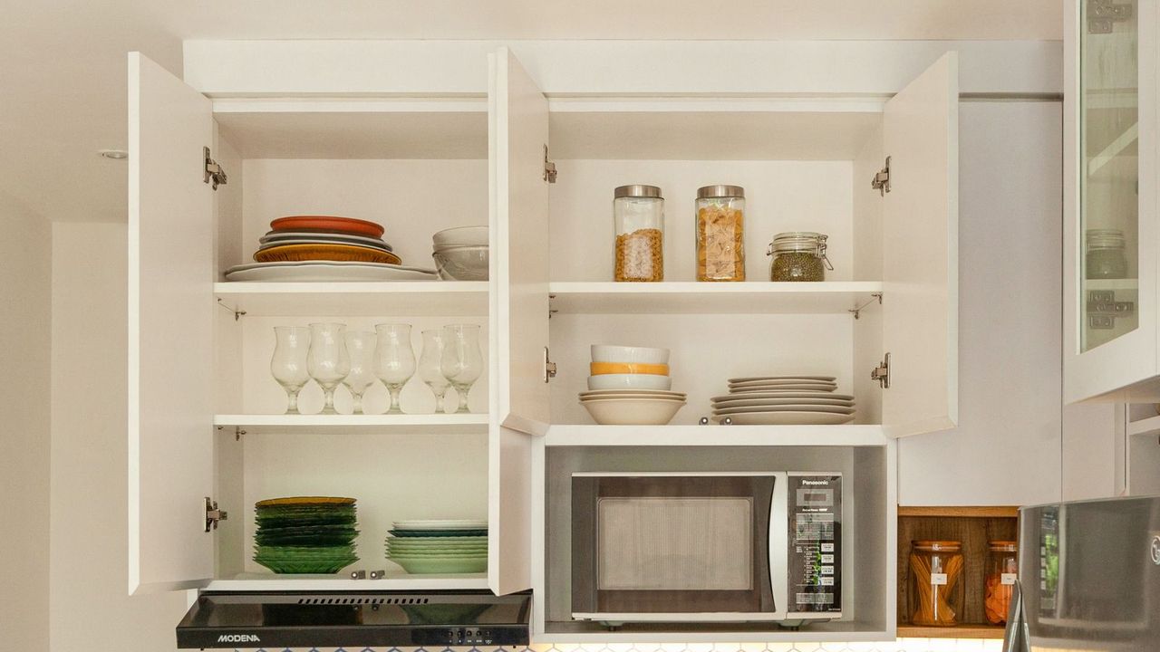 Open kitchen cabinets with dishes and jars in order
