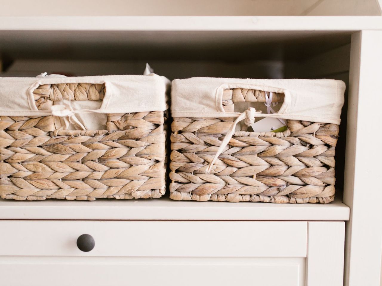 Woven storage baskets lined up on a white shelf